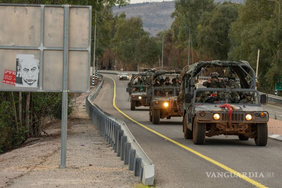 $!Vehículos militares israelíes pasan junto a un cartel con dibujos animados del primer ministro Benjamin Netanyahu en el norte de Israel