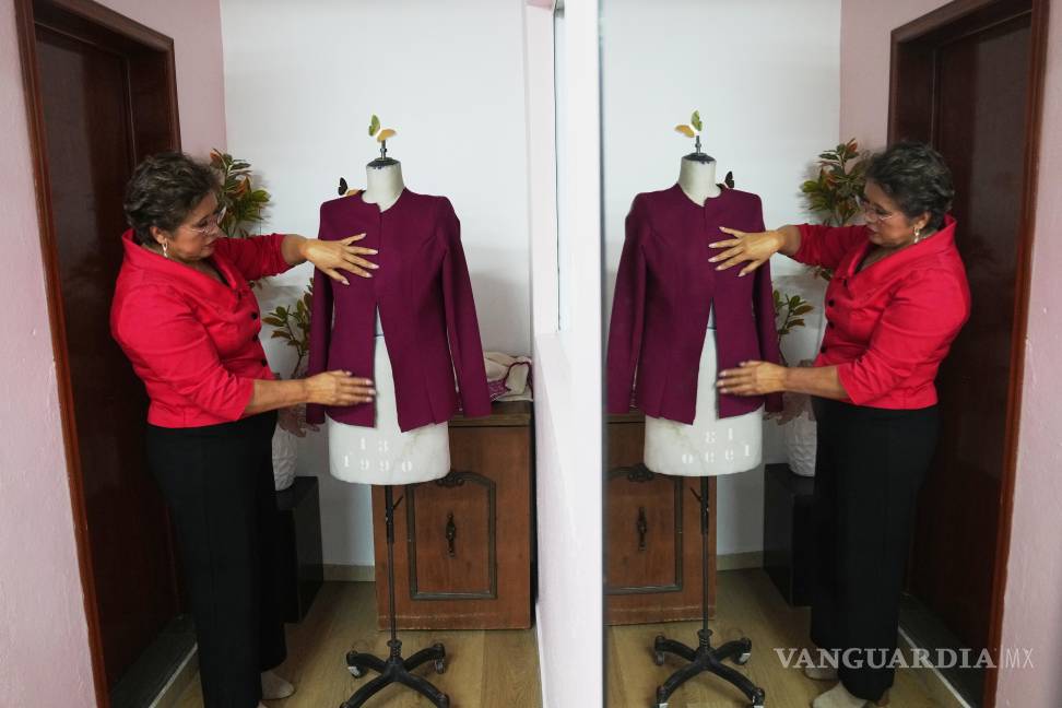 $!Olivia Trujillo, reflejada en un espejo, crea una prenda para la presidenta mexicana Claudia Sheinbaum en su taller de Ciudad de México.