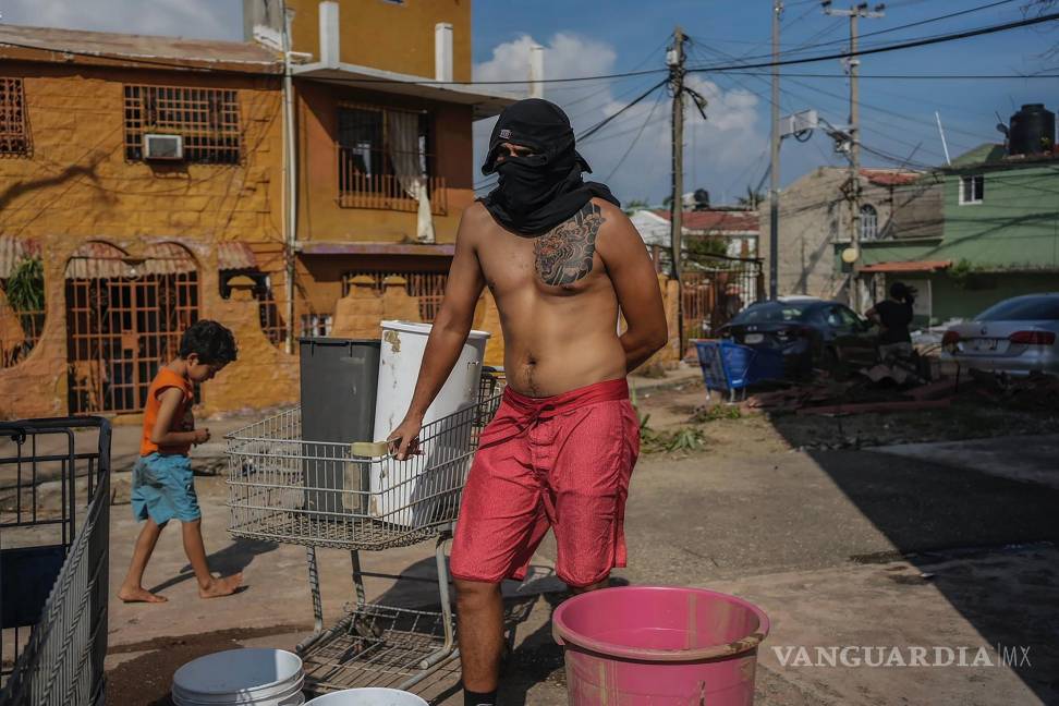 $!Un residente que esconde su rostro con una camisa espera su turno para recoger agua de un pozo público después del huracán Otis en Acapulco, México.