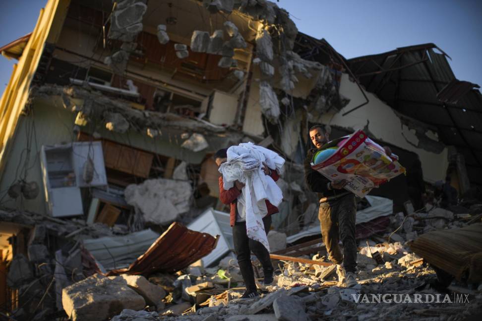 $!Residentes trasladan sus pertenencias desde su vivienda en un edificio destrozado por un potente sismo, en Samandag.