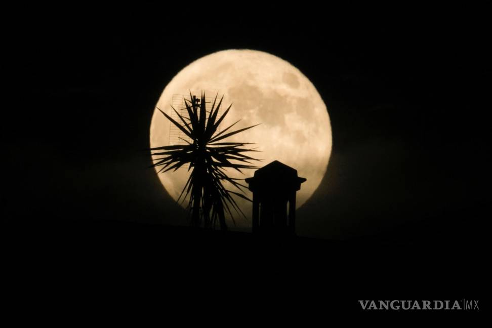 $!Una superluna se eleva desde un techo en Roma. Durante el fenómeno conocido como la “Luna de fresa”.