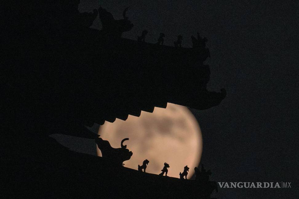 $!Las decoraciones del techo en la torre de la esquina de la Ciudad Prohibida que representan bestias sagradas se recortan contra una superluna en Beijing, China.