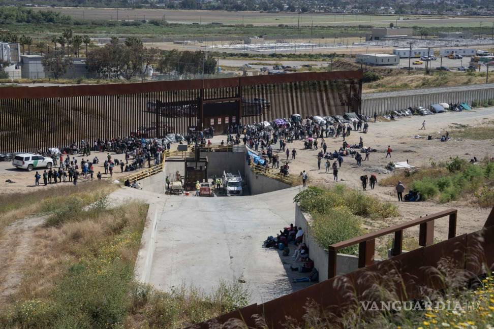 $!Migrantes esperan a las autoridades americanas, tras pasar el muro fronterizo que divide a México-Estados Unidos en la frontera con Tijuana, Baja California.