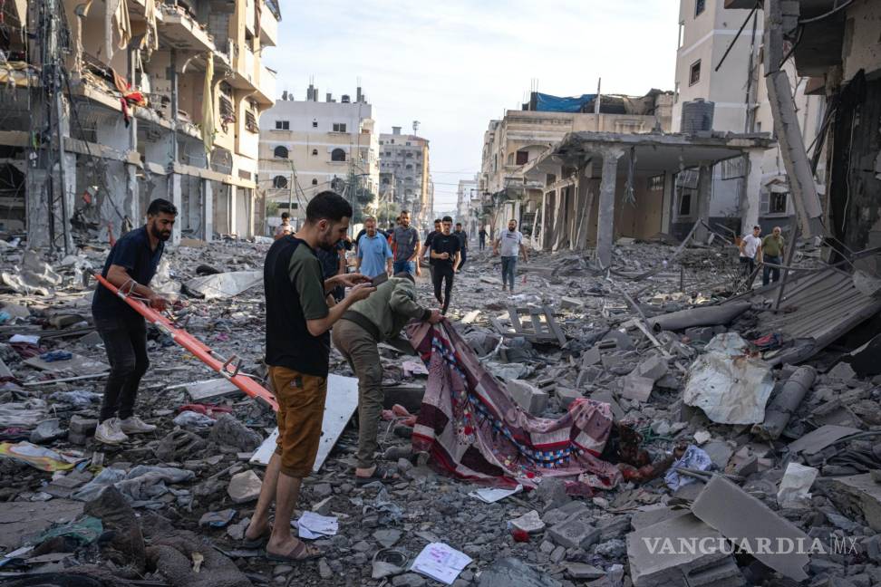 $!Varios palestinos recogen cadáveres de entre los escombros tras un bombardeo israelí en la Ciudad de Gaza.