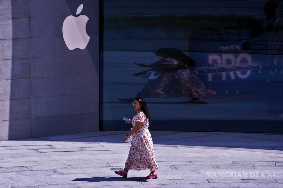 $!Una mujer camina frente a una tienda Apple que promociona su último iPhone 16, en un popular distrito comercial de Shanghái, China.