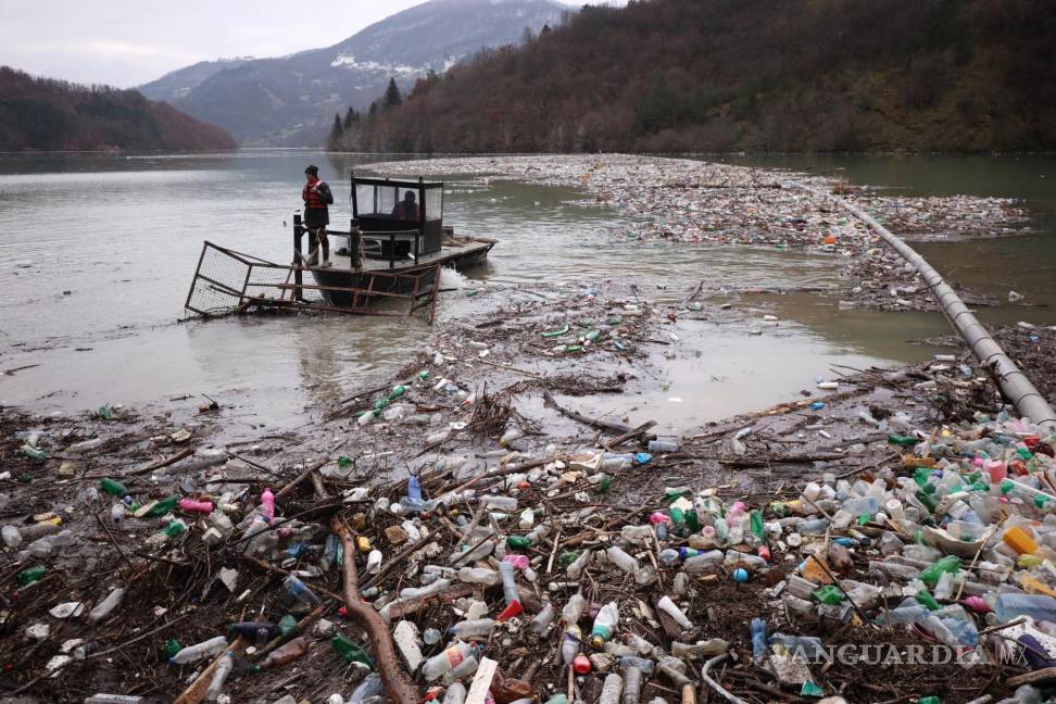 $!Los trabajadores de una empresa de servicios públicos empujan los desechos a la orilla del río Lim, cerca de Priboj, Serbia.