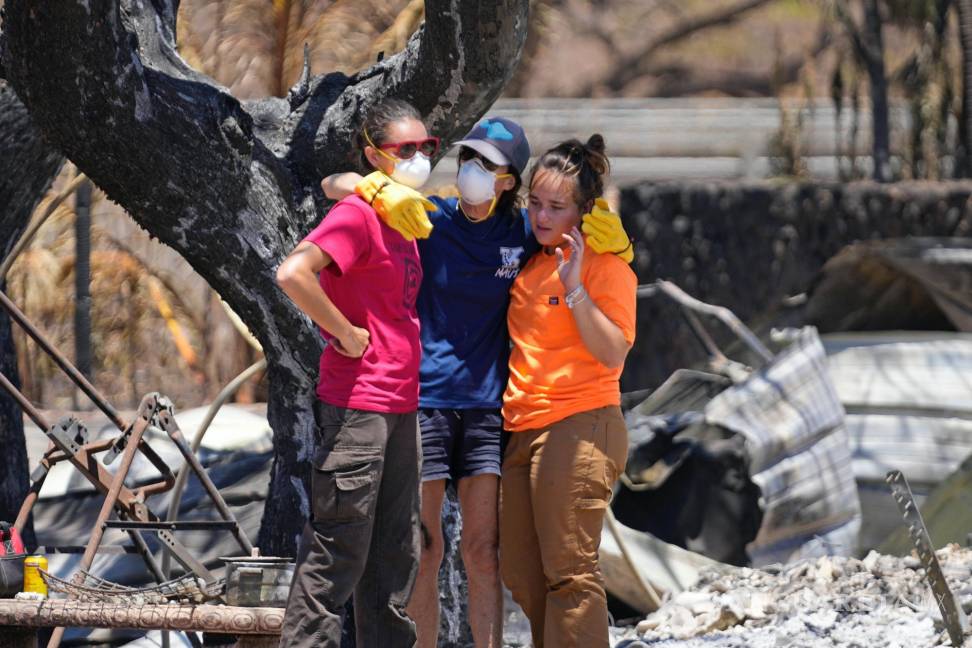$!Las mujeres se abrazan después de excavar entre los escombros de una casa destruida por un incendio forestal en Lahaina, Hawái.