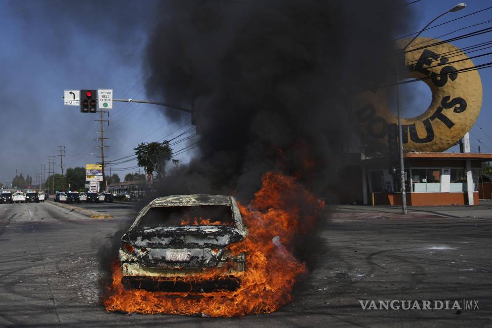 $!Un vehículo arde en llamas durante una protesta después de que autoridades federales de inmigración llevaron a cabo una redada, el sábado 7 de junio de 2025, en Compton, California. (AP Foto/Eric Thayer)