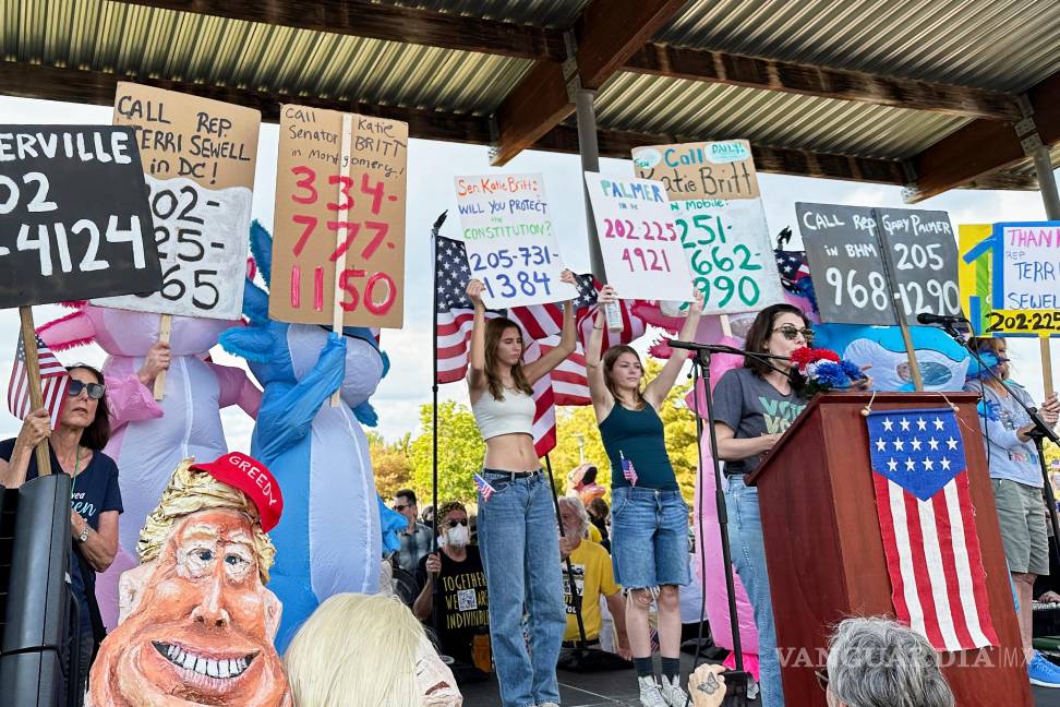 $!Becca Rothman y manifestantes con carteles con los números de teléfono de las oficinas de los representantes electos de Alabama durante la protesta “No Kings”.