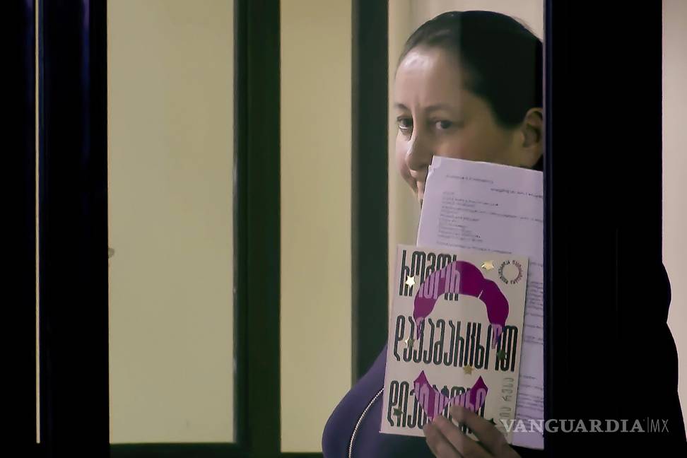 $!Mzia Amaghlobeli en la jaula de los acusados en un tribunal de Batumi, Georgia y sostiene un libro de la premio Nobel de la Paz Maria Ressa-
