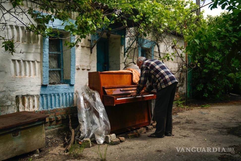 $!Anatolii Virko toca el piano ante una casa probablemente dañada por un ataque ruso en el poblado de Velyka Kostromka, Ucrania, el jueves 19 de mayo de 2022.