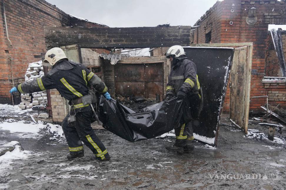 $!Los bomberos transportan el cuerpo de un residente que murió en un incendio cuando un dron ruso impactó su casa en un vecindario residencial en Kharkiv.