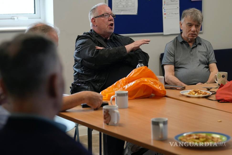 $!Barrie Stradling, a la izquierda, habla durante el almuerzo semanal de unos 20 jubilados en el centro comunitario Tredegar de Bow en el este de Londres.