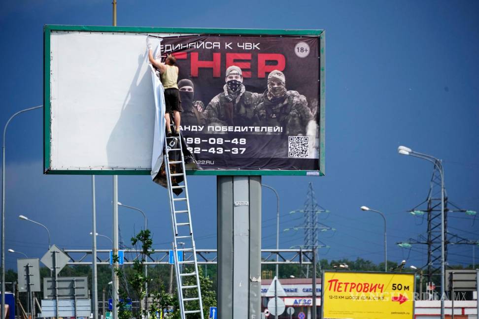 $!Un hombre quita el cartel que dice “Únase a nosotros en Wagner” sobre una carretera en las afueras de San Petersburgo, Rusia.