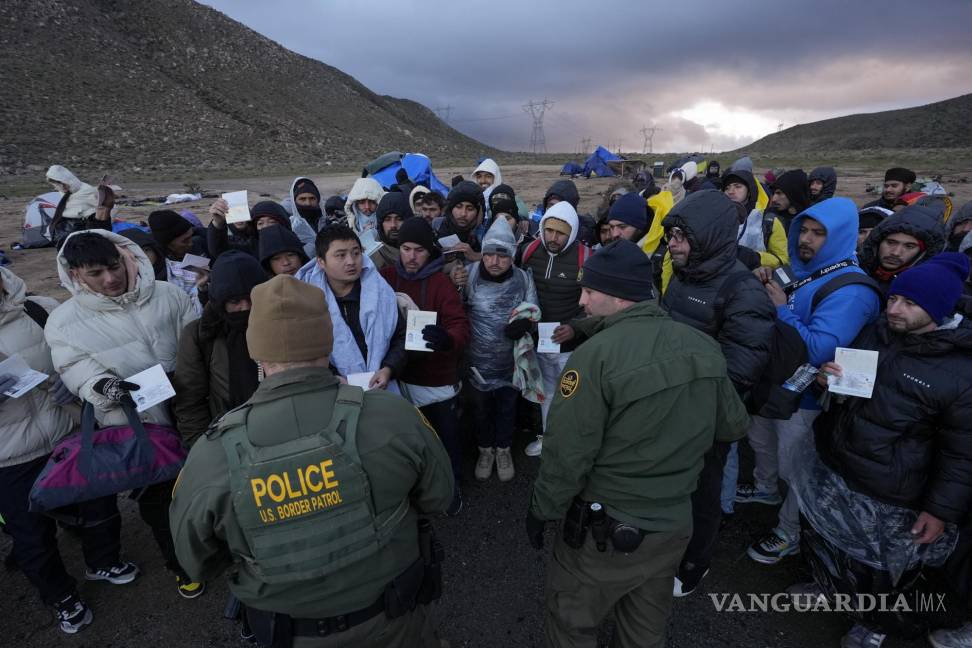 $!Agentes de la Patrulla Fronteriza hablan con migrantes que buscan asilo en un campamento improvisado después de cruzar la frontera con México.