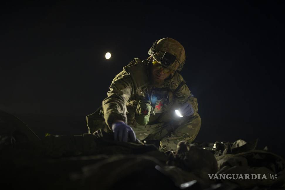 $!Oleksii Yukov examina el cuerpo de un soldado ruso que recogió en el frente en la región de Slaviansk, Ucrania.