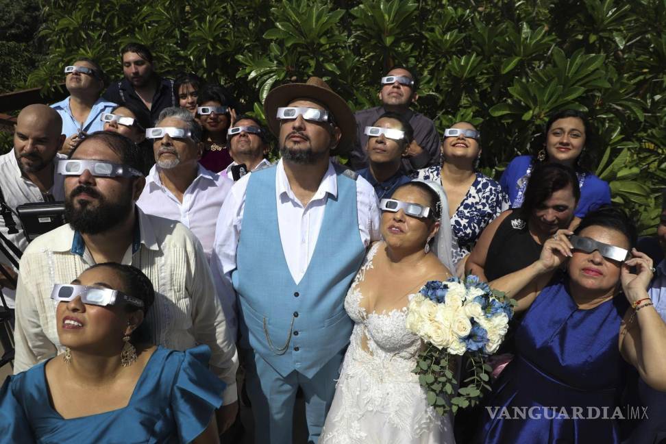 $!Los novios Isaac Medina (centro) y Jazmin González observan un inusual eclipse solar antes de la ceremonia de su boda, en Mérida, México, el 14 de octubre de 2023.