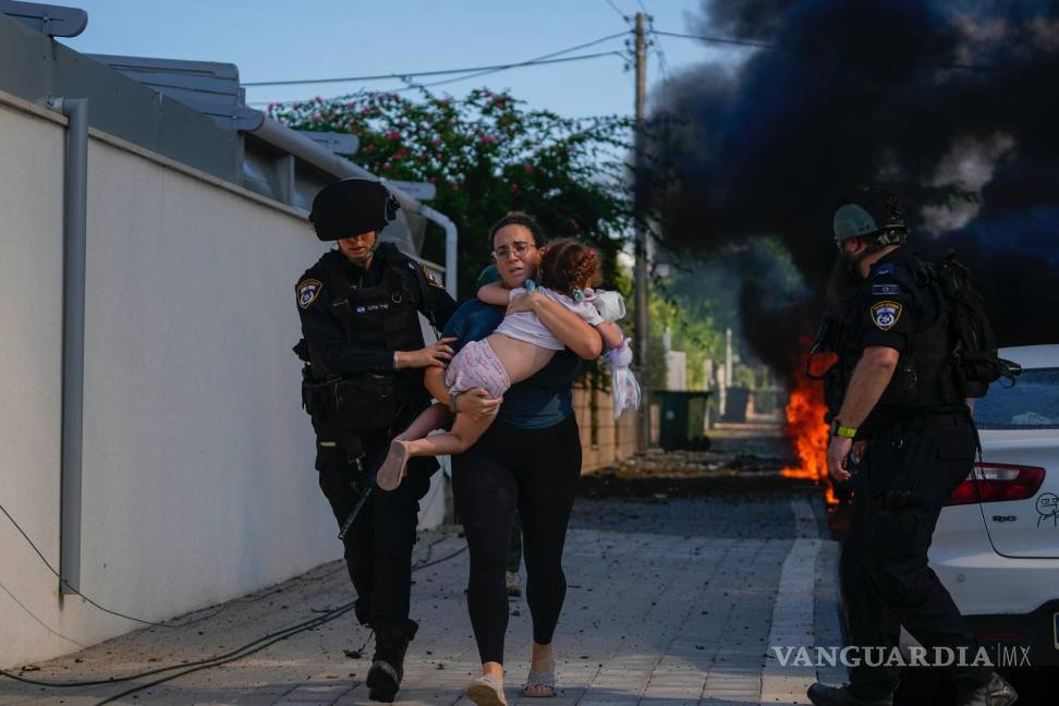 $!Policías israelíes evacuan a una mujer y a un niño de un lugar alcanzado por un cohete disparado desde Gaza, en Ashkelon, Israel, el 7 de octubre de 2023.