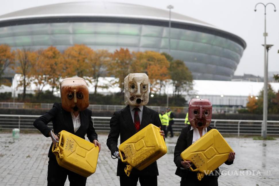 $!Activistas sostienen bidones después de derramar petróleo falso durante su actuación cerca del lugar donde se llevará a cabo la conferencia climática de la ONU en Glasgow, Escocia. AP/Scott Heppell