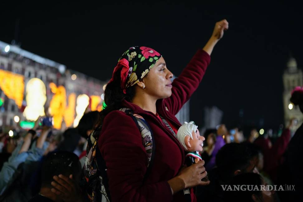 $!Una partidaria de AMLO sostiene un muñeco con su imagen mientras lo escucha dar el grito anual del Día de la Independencia desde el balcón del Palacio Nacional.