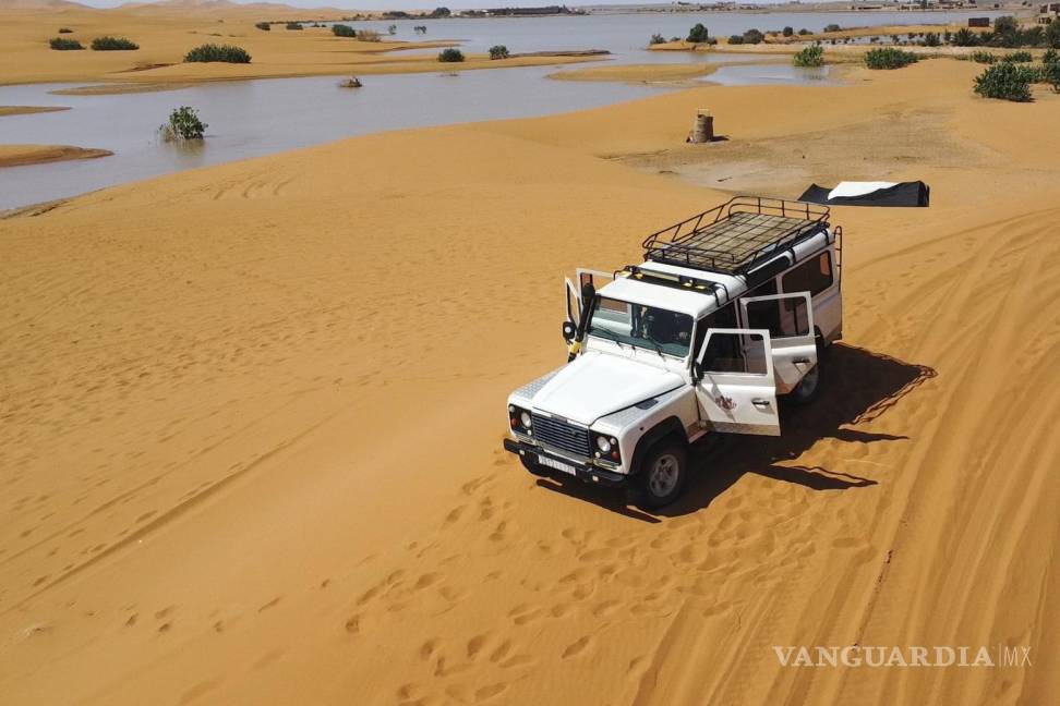 $!Un vehículo transporta turistas por las dunas de arena junto a un lago provocado por las fuertes lluvias en la ciudad desértica de Merzouga, cerca de Rachidia.