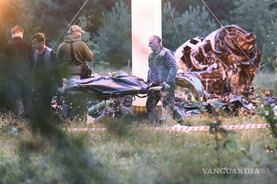 $!Dos personas trasladan una bolsa para cadáveres del lugar donde se estrelló un avión privado, cerca de la localidad de Kuzhenkino, en la región de Tver, Rusia.