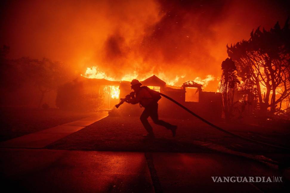 $!Un bombero lucha contra el incendio de Palisades mientras quema una estructura en el vecindario de Pacific Palisades en Los Ángeles.