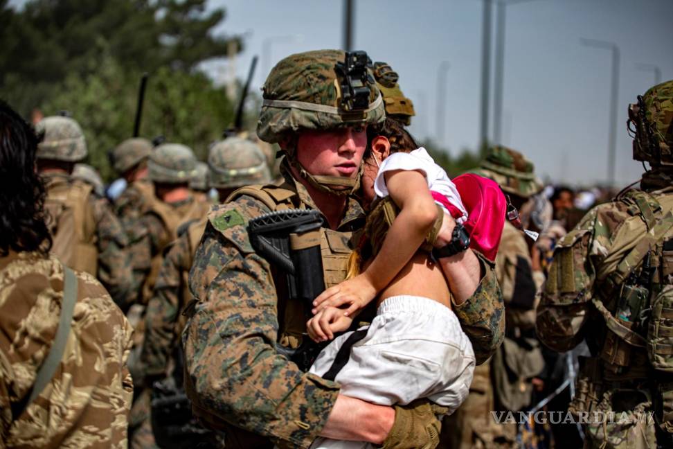 $!Un infante de marina asignado a la 24a Unidad Expedicionaria de Infantería de Marina que lleva a una niña en la puerta del aeropuerto internacional Hamid Karzai, en Kabul, Afganistán. EFE/EPA/U.S. Marine Corps