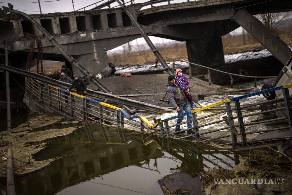 $!La combatiente Valery, de 37 años, carga a un niño mientras ayuda a una familia a cruzar un puente que fue destruido por artillería, el miércoles 2 de marzo de 2022, en Kiev. (AP Foto/Emilio Morenatti)