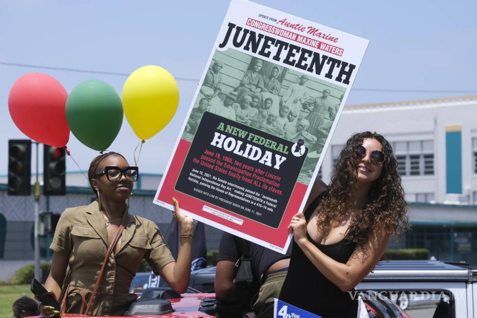 $!Las personas sostienen un cartel en su automóvil en un desfile de automóviles para conmemorar el 19 de junio, el 19 de junio de 2021, en Inglewood, California.
