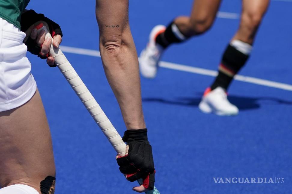 $!La irlandesa Nicola Daly busca pasar el balón mientras se ve un tatuaje que dice “VIVO” en su brazo derecho durante un partido de hockey femenino contra Alemania. (AP Photo/John Minchillo)