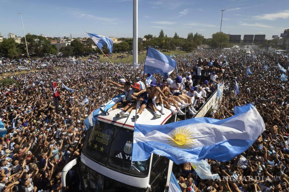 $!El equipo de fútbol argentino que ganó el título de la Copa del Mundo viaja en la parte superior de un autobús durante su desfile de bienvenida en Buenos Aires.
