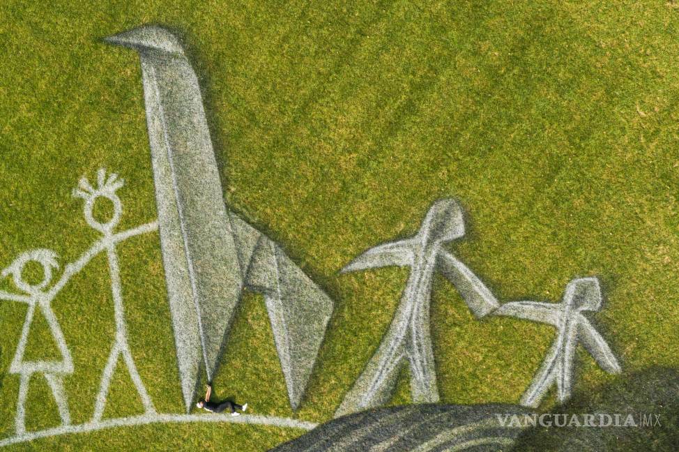 $!El artista franco-suizo Saype (Guillaume Legros) posa en su gigantesca pintura efímera landart titulada “Mundo en progreso II” que representa a dos niños dibujando y construyendo con origami su mundo ideal, en la Sede de las Naciones Unidas (ONU) en Nueva York. AP/Valentin Flauraud/Keystone