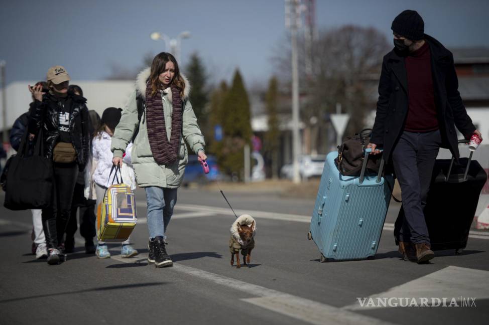 $!Una mujer camina con su perro para cruzar la frontera de Ucrania.