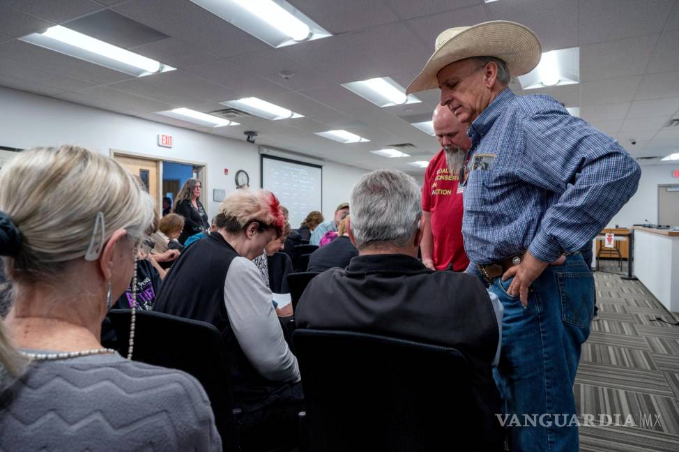 $!Curt Miller, a la derecha, pastor de la Iglesia East Mountain Cowboy, ora con los asistentes a la reunión del Concejo Municipal, en Edgewood, Nuevo México.