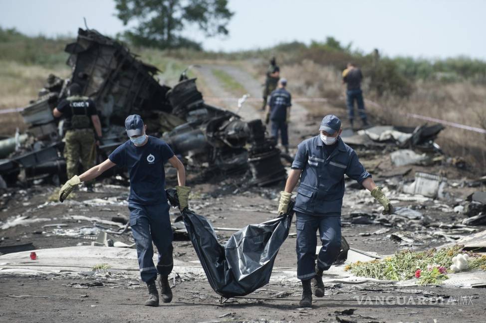 $!Los trabajadores de emergencia ucranianos llevan el cuerpo de una víctima en una bolsa para cadáveres en el lugar del accidente del vuelo MH17 de Malaysia Airlines.