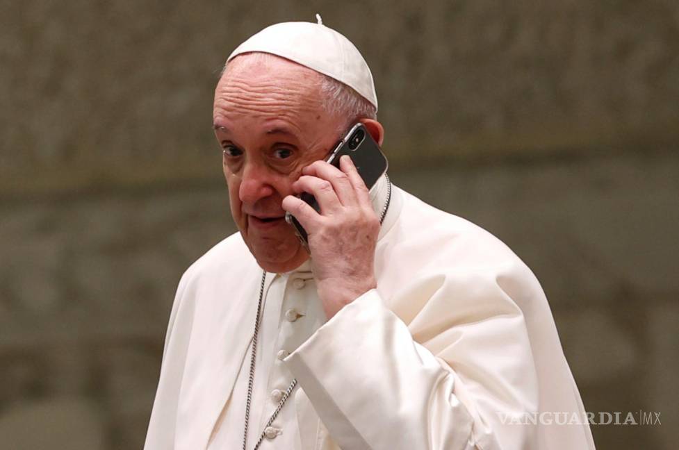 $!El papa Francisco habla por un teléfono celular que le entregó su asistente Piergiorgio Zanetti, al cabo de la audiencia general semanal en la Sala Paulo VI en el Vaticano. AP/Riccardo De Luca