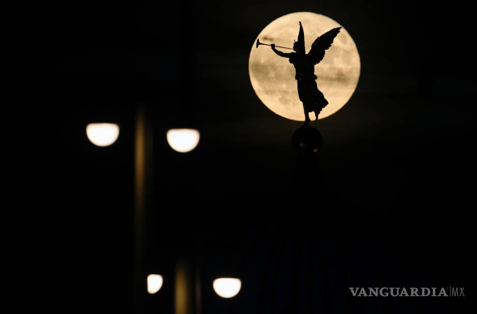 $!La luna llena sale detrás del ángel “Fama” en la Academia de Bellas Artes en Desden, Alemania. Durante un fenómeno conocido como la “ Strawberry Moon”.