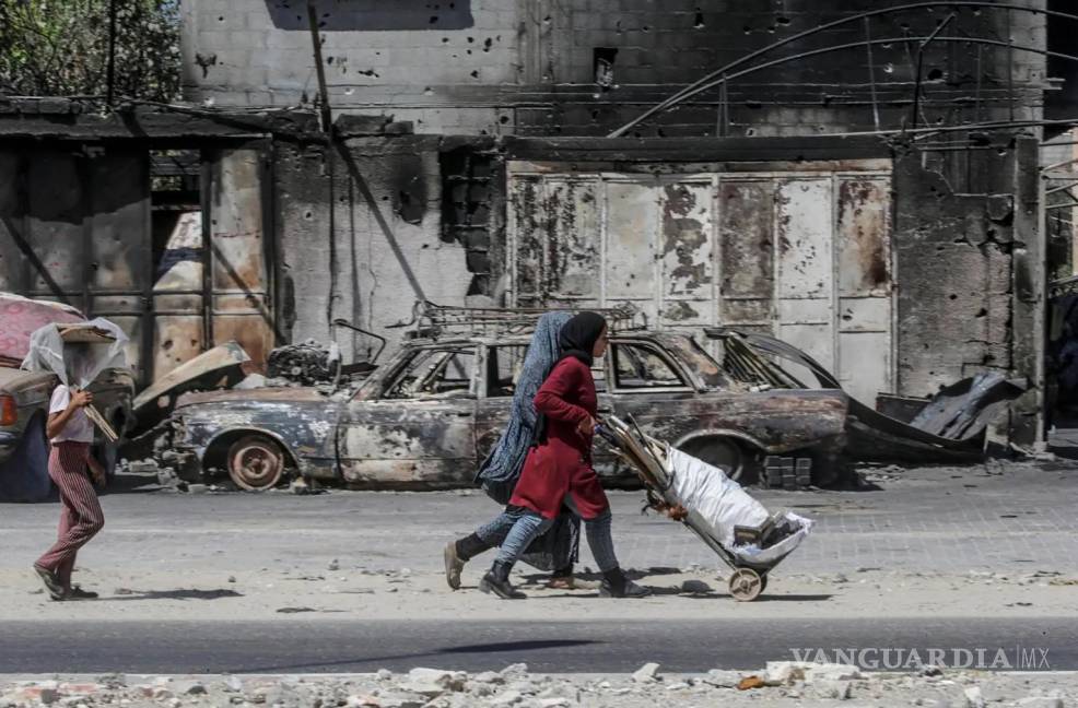 $!Palestinos desplazados internamente caminan cerca de vehículos y edificios destruidos en Khan Yunis, sur de la Franja de Gaza, el 19 de septiembre de 2024.