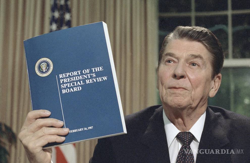 $!El presidente Ronald Reagan sostiene una copia del informe de la Comisión Tower sobre el asunto Irán-Contra en Washington, el 13 de agosto de 1987.