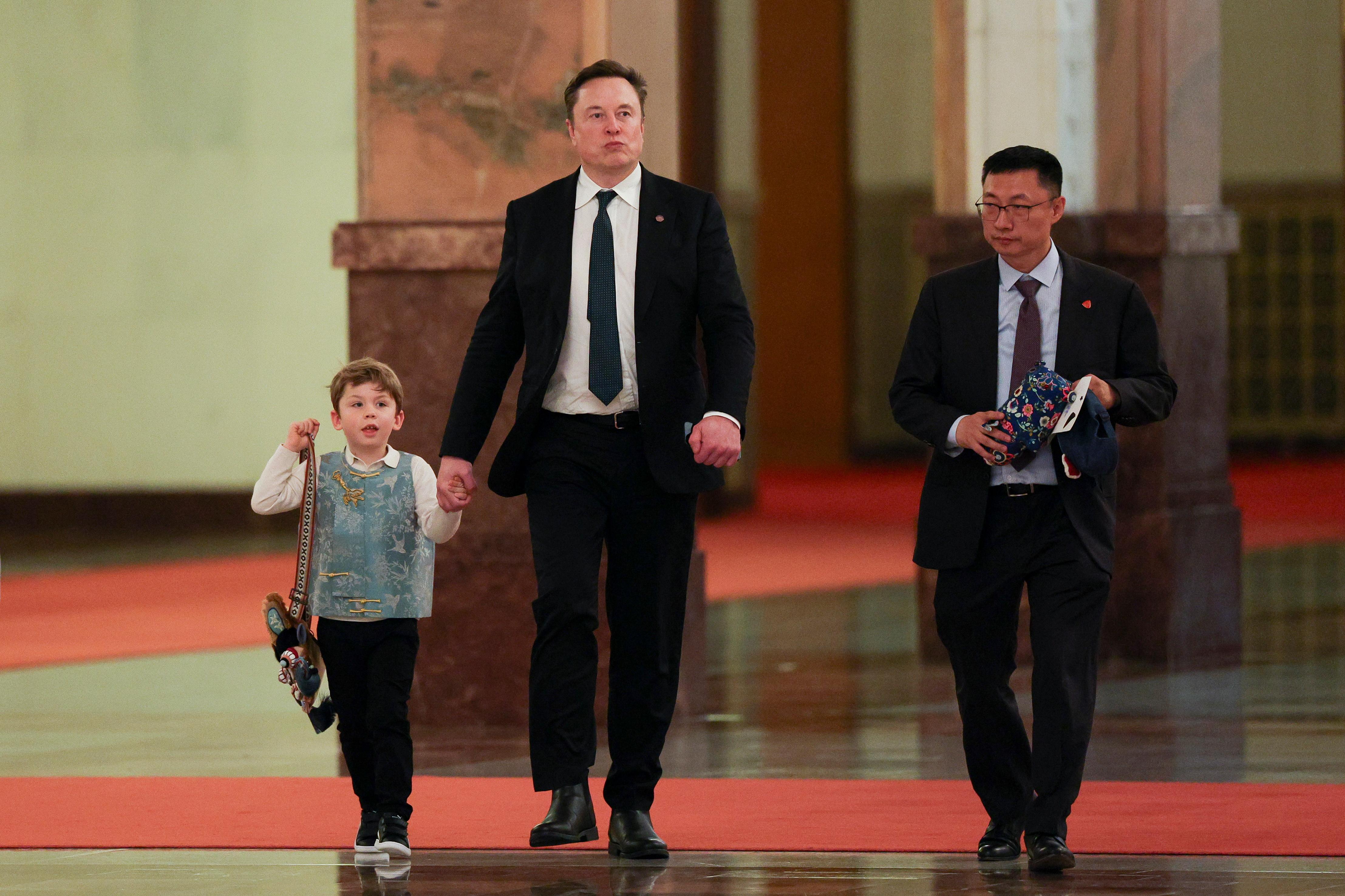 El director ejecutivo de Tesla, Elon Musk, y su hijo X Æ A-Xii caminan mientras el primer ministro chino, Li Qiang, se reúne con directores ejecutivos estadounidenses en Pekín, China.