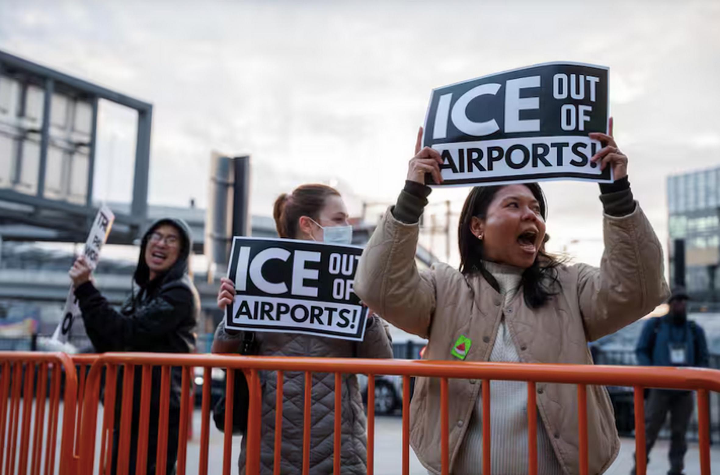 Varias personas portan pancartas frente a la Terminal 4 del Aeropuerto John F. Kennedy durante una protesta contra los agentes del ICE.