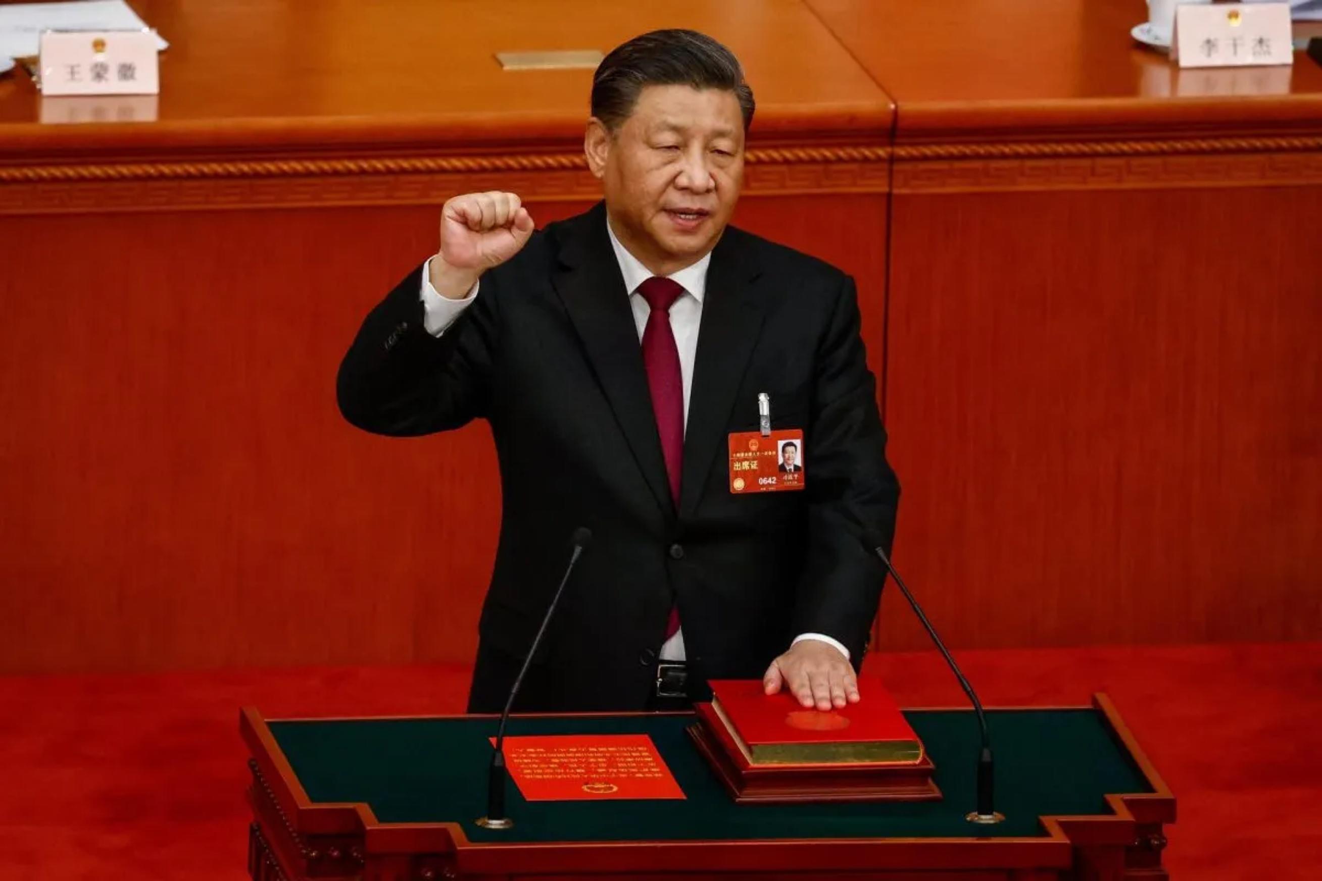 El presidente chino Xi Jinping saluda, puño en al término de la Asamblea Nacional Popular china que le ha designado para un tercer mandato.